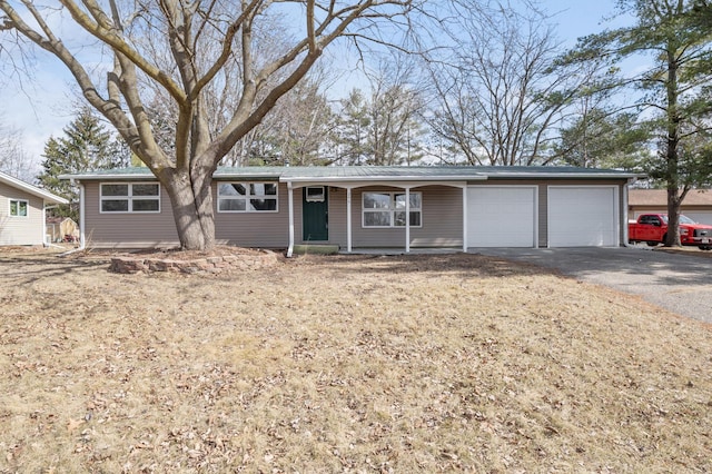 ranch-style house with driveway, metal roof, and a garage