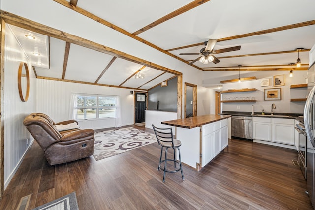 kitchen featuring stainless steel dishwasher, open floor plan, white cabinetry, lofted ceiling with beams, and dark wood finished floors