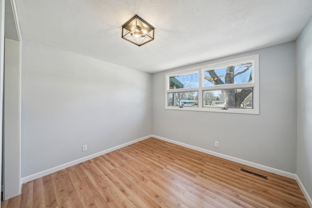 unfurnished room featuring baseboards, visible vents, and light wood-type flooring