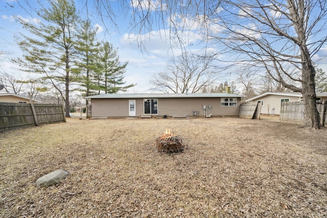 rear view of house featuring fence and a fire pit