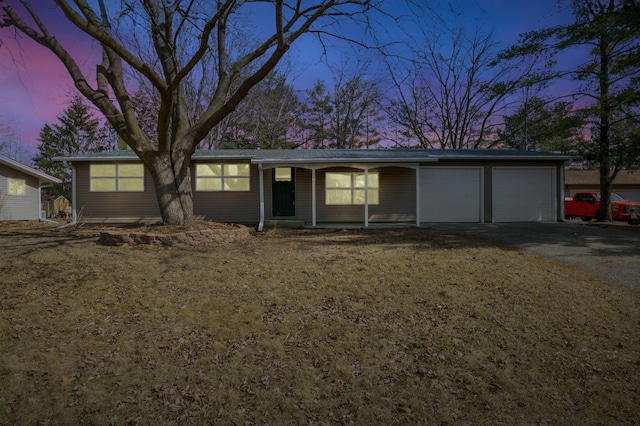 ranch-style house featuring driveway, metal roof, and a garage