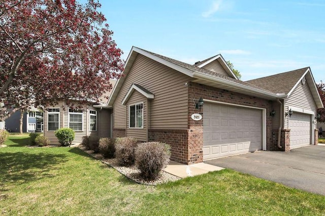 view of side of property with brick siding, an attached garage, asphalt driveway, a lawn, and roof with shingles
