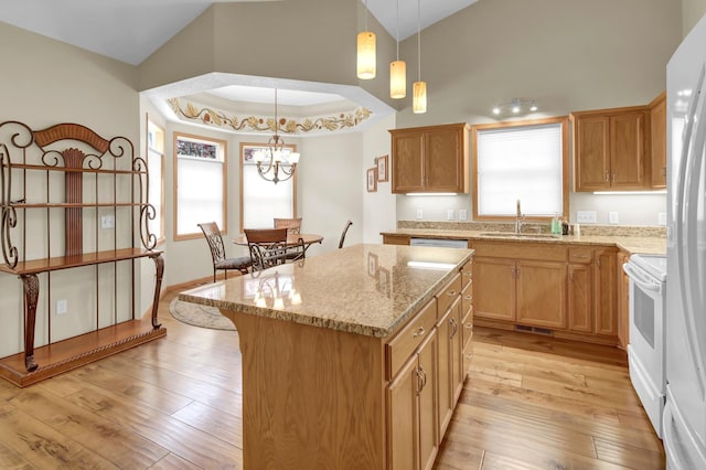 kitchen featuring white appliances, a sink, light stone counters, a kitchen island, and light wood-style flooring