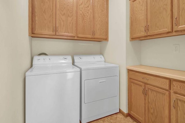 clothes washing area featuring washer and dryer, cabinet space, and light tile patterned flooring