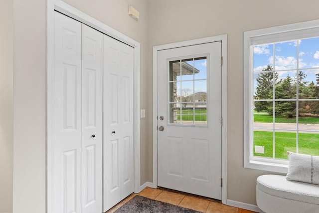 doorway to outside featuring baseboards, light tile patterned flooring, and a wealth of natural light