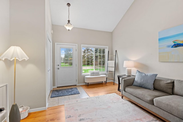 foyer with high vaulted ceiling, baseboards, and light wood-type flooring
