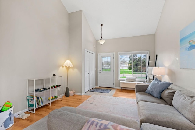living room with high vaulted ceiling, baseboards, and wood finished floors