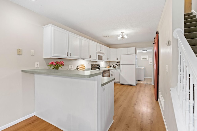 kitchen featuring baseboards, white cabinets, a peninsula, light wood finished floors, and white appliances