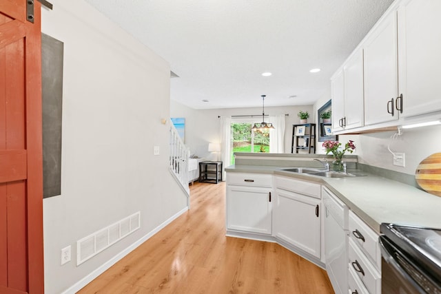 kitchen with visible vents, a peninsula, light wood-type flooring, white cabinets, and a sink