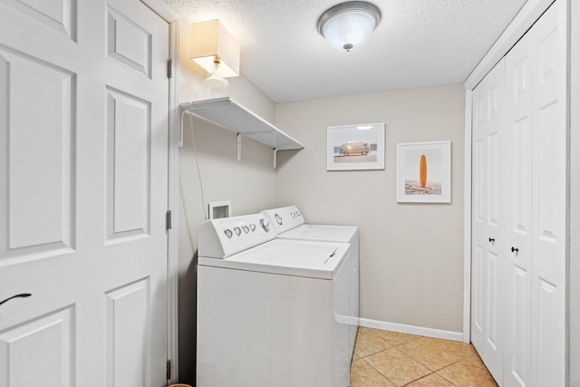 clothes washing area with light tile patterned floors, laundry area, a textured ceiling, and washer and dryer