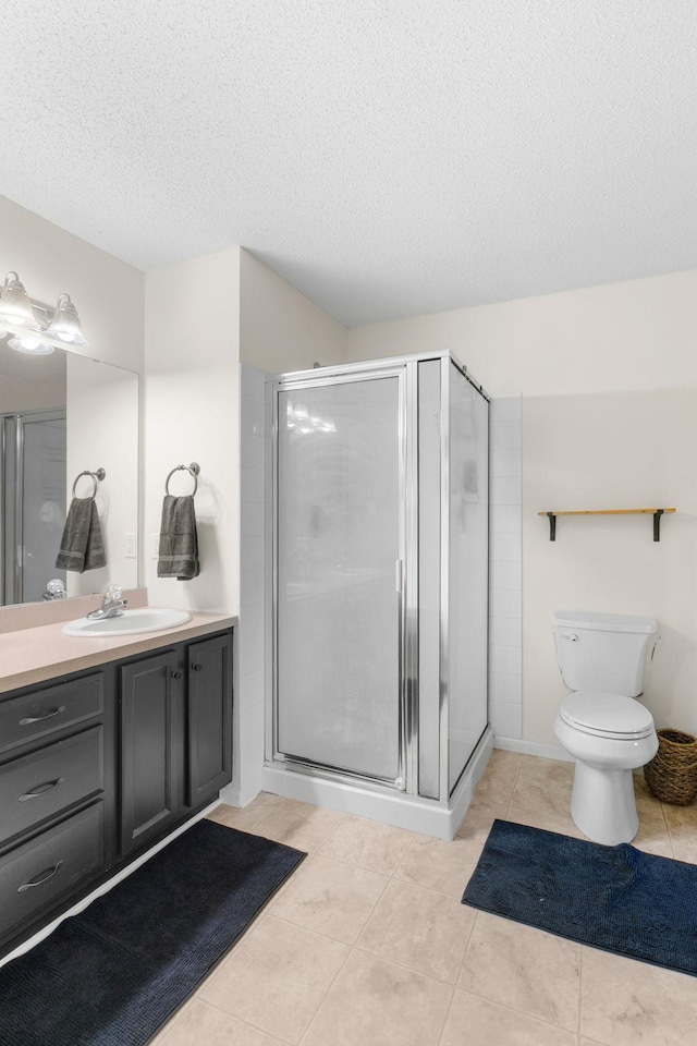 full bathroom featuring vanity, a textured ceiling, tile patterned floors, and a shower stall