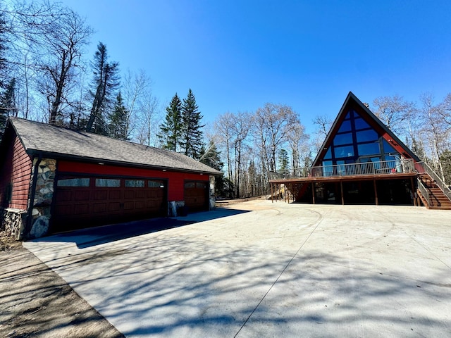 63521 County Road 2, Warroad, MN 56763 - view of side of property with a detached garage, a wooden deck, stairway, and stone siding