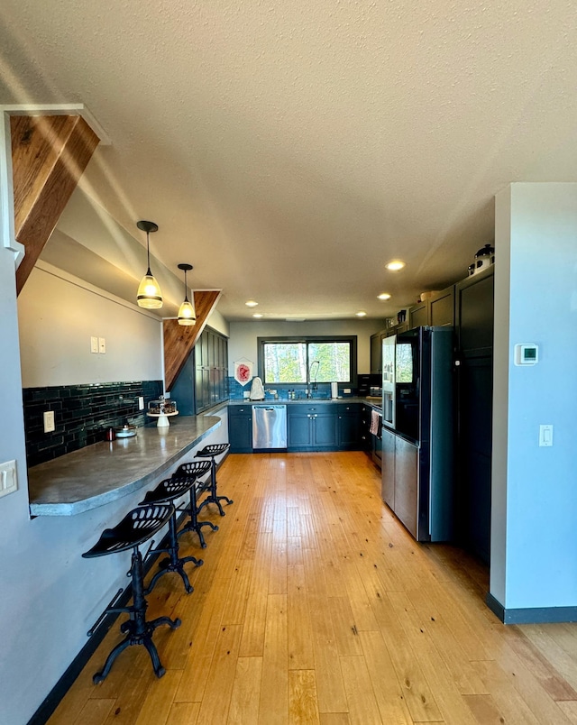63521 County Road 2, Warroad, MN 56763 - kitchen with decorative light fixtures, dishwasher, a peninsula, light wood finished floors, and black fridge