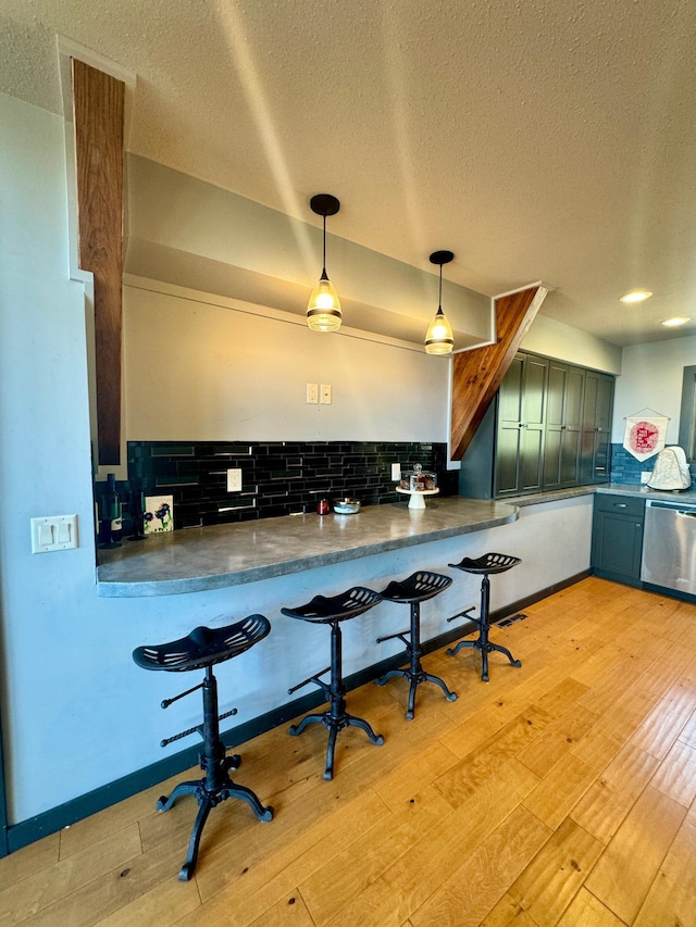 63521 County Road 2, Warroad, MN 56763 - kitchen featuring stainless steel dishwasher, a textured ceiling, backsplash, and light wood-type flooring