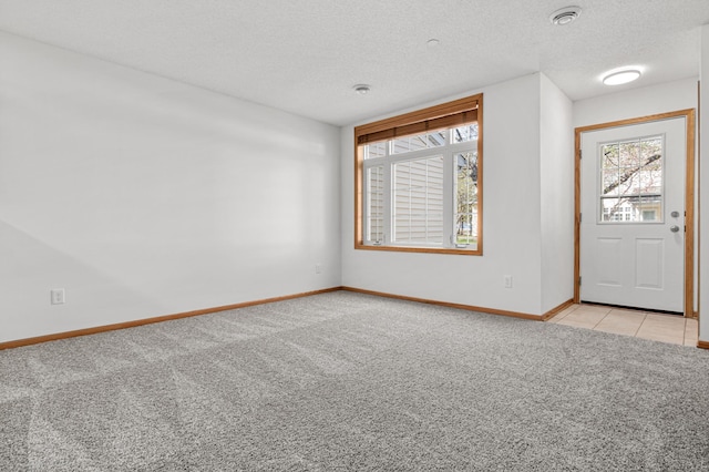 foyer entrance with a textured ceiling, baseboards, light carpet, and a wealth of natural light