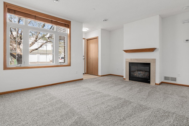unfurnished living room featuring visible vents, carpet, baseboards, and a premium fireplace