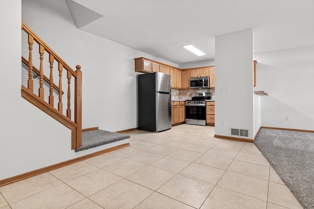 kitchen with decorative backsplash, light countertops, light tile patterned floors, baseboards, and stainless steel appliances