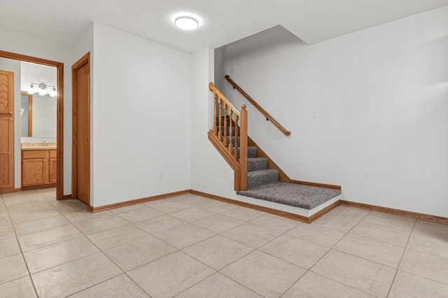 interior space featuring a sink, light tile patterned floors, baseboards, and stairs