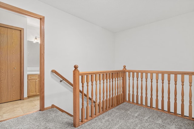 interior space featuring baseboards, light colored carpet, and an upstairs landing