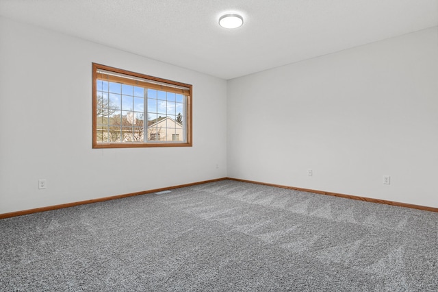 carpeted empty room featuring baseboards