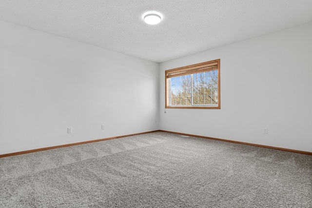carpeted empty room featuring a textured ceiling and baseboards