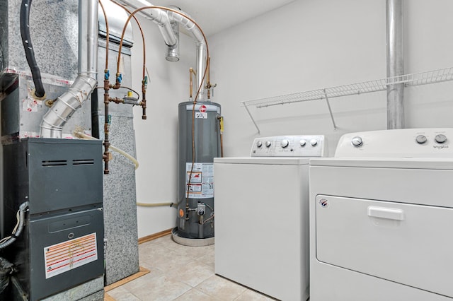 clothes washing area featuring laundry area, light tile patterned floors, gas water heater, and washing machine and clothes dryer