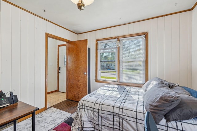 bedroom featuring crown molding, wood walls, and wood finished floors