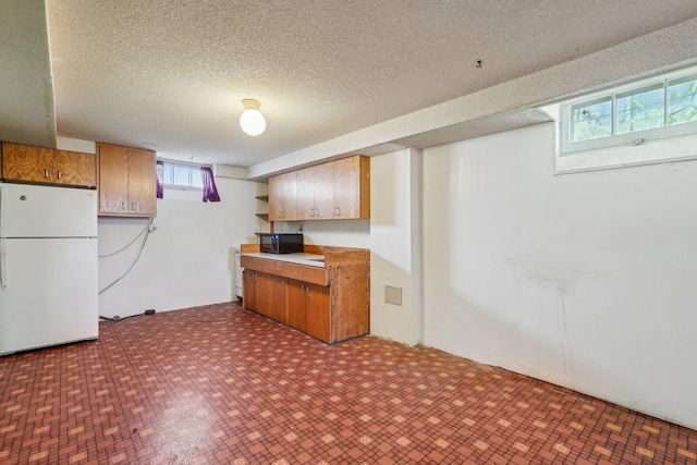 kitchen with freestanding refrigerator, black microwave, a textured ceiling, light countertops, and open shelves