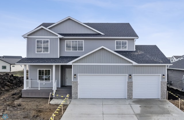 5875 11th St W, West Fargo, ND 58078 - view of front of home with roof with shingles, covered porch, concrete driveway, and stone siding