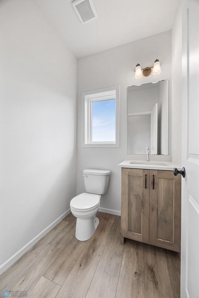 5875 11th St W, West Fargo, ND 58078 - half bath featuring vanity, toilet, baseboards, wood finished floors, and visible vents