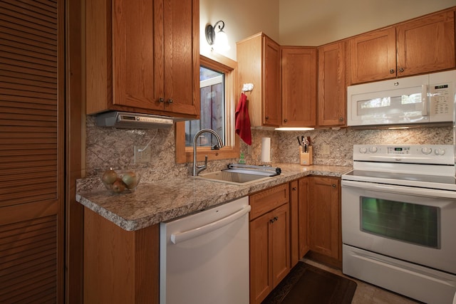 kitchen featuring white appliances, a sink, tasteful backsplash, brown cabinetry, and light countertops