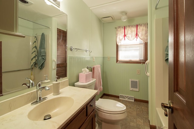bathroom with heating unit, toilet, vanity, a shower, and wainscoting