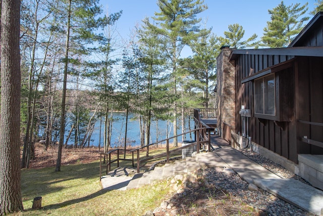 view of grassy yard featuring a deck with water view
