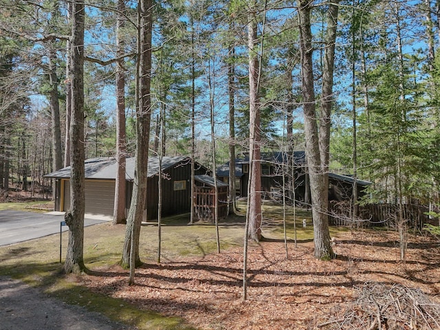view of yard with a garage, driveway, an outbuilding, and fence
