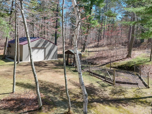 view of yard featuring a garage, an outbuilding, a garden, and driveway
