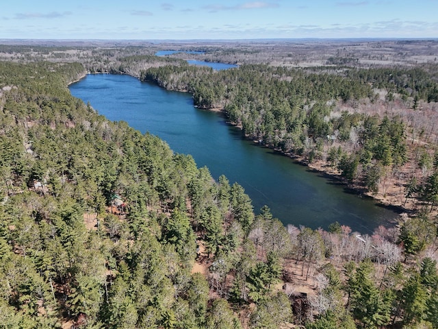aerial view of property and surrounding area featuring a heavily wooded area and a large body of water