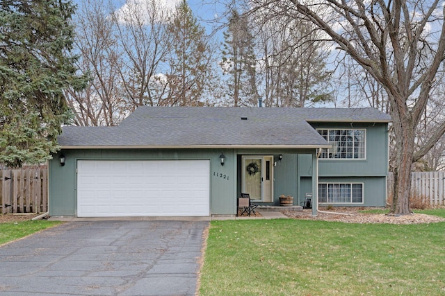 view of front of home with fence, a shingled roof, a front lawn, a garage, and driveway