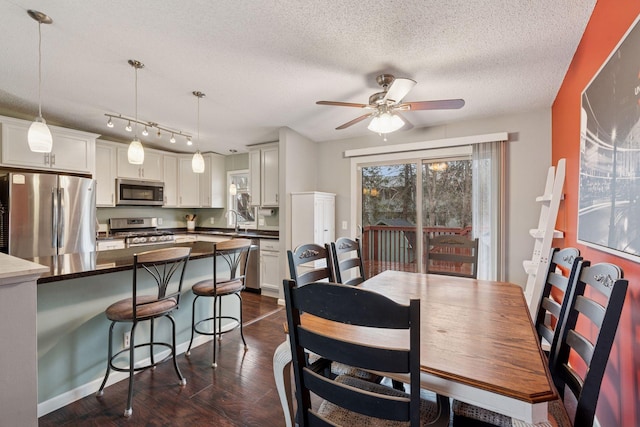 dining room featuring a textured ceiling, ceiling fan, and dark wood-style floors