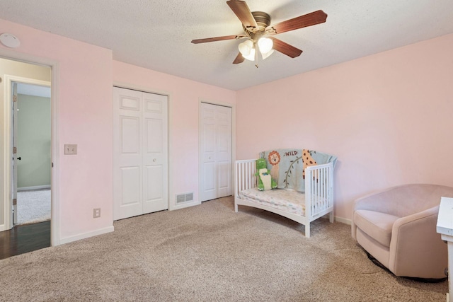 living area featuring ceiling fan, a textured ceiling, visible vents, baseboards, and carpet flooring