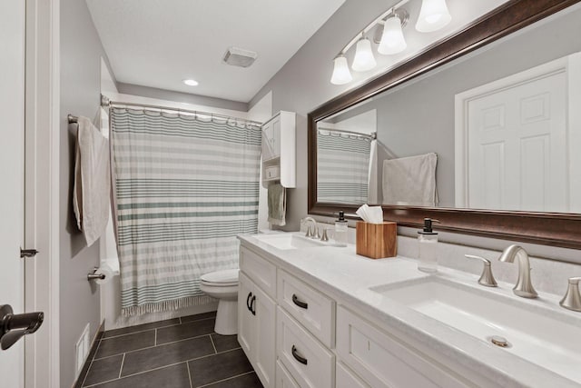 bathroom with a sink, tile patterned flooring, toilet, and double vanity
