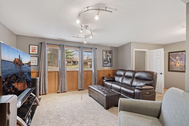 living room with a wainscoted wall, wood walls, a textured ceiling, and light colored carpet