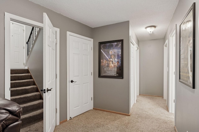 hallway with baseboards, carpet flooring, a textured ceiling, and stairway