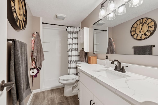 bathroom featuring vanity, wood finished floors, curtained shower, toilet, and a textured ceiling