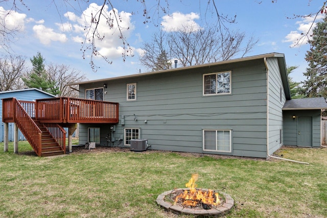 back of house with a lawn, a wooden deck, a fire pit, and stairway