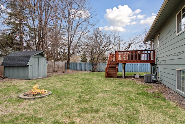 view of yard featuring a storage shed, a wooden deck, stairway, a fenced backyard, and a fire pit