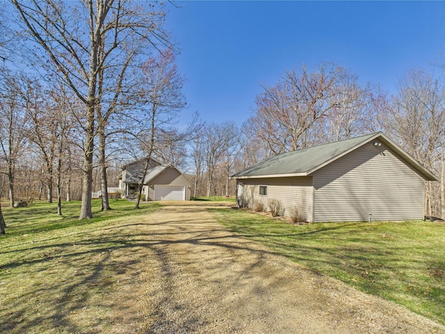 view of side of property featuring a detached garage, an outdoor structure, and a lawn