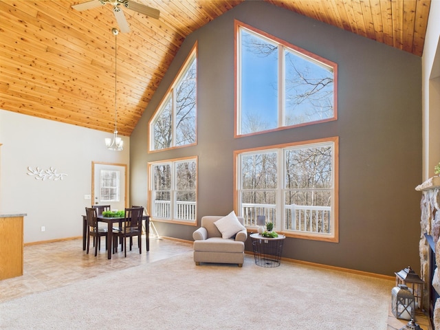 living area with carpet flooring, high vaulted ceiling, a stone fireplace, baseboards, and wood ceiling