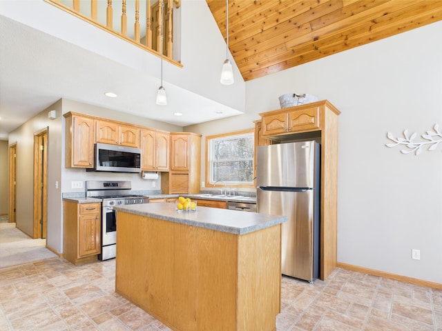 kitchen featuring a kitchen island, baseboards, a sink, decorative light fixtures, and stainless steel appliances