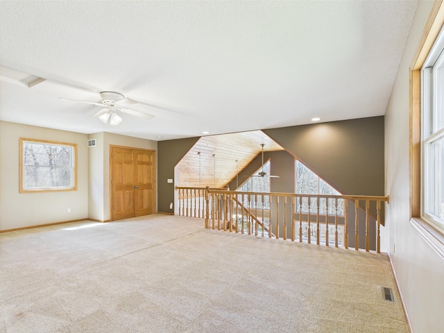 additional living space featuring a ceiling fan, baseboards, visible vents, and carpet