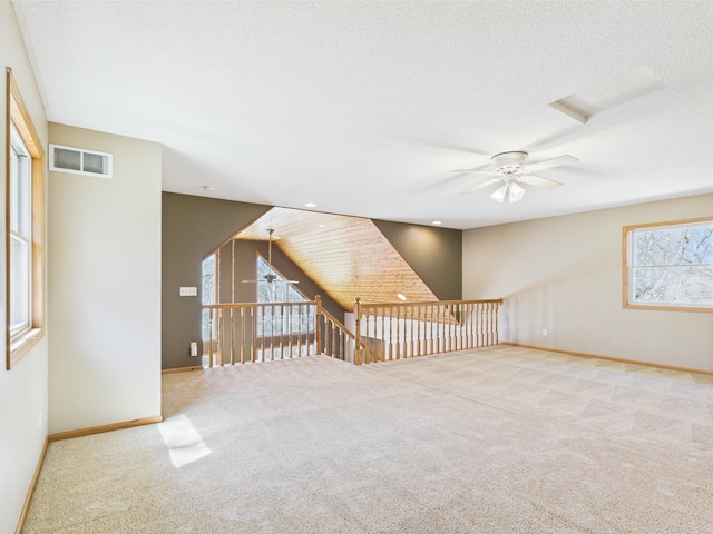 additional living space featuring visible vents, carpet floors, baseboards, a textured ceiling, and a ceiling fan